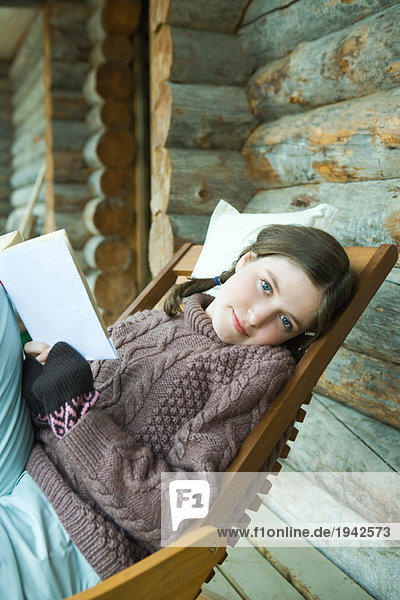 Teenagermädchen liest Buch  lächelt vor der Kamera  gekleidet in Winterkleidung