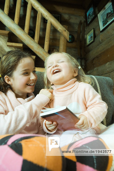 Mädchen und Kleinkind auf der Couch sitzend  lachend