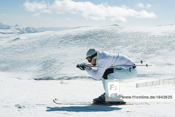 Junge Skifahrerin kauernd  Seitenansicht  Ganzkörperporträt
