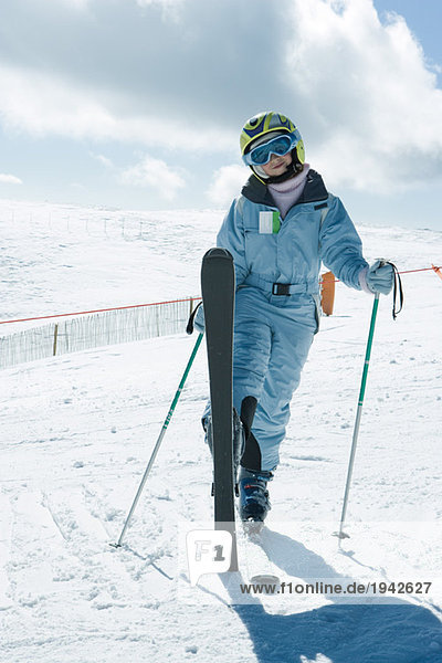 Junger Skifahrer stehend mit einem Bein nach oben  lächelnd vor der Kamera  Ganzkörperporträt