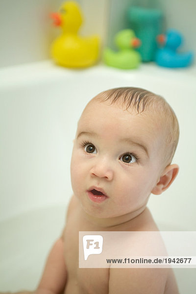 Nacktes Baby in der Badewanne sitzend  aufblickend  große Augen