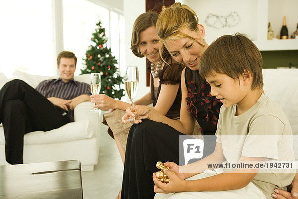 Junge und Familie sitzen auf der Couch  Blick auf Weihnachtsschmuck  Weihnachtsbaum im Hintergrund