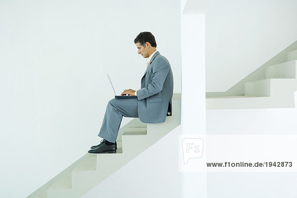 Mann auf der Treppe sitzend  mit Laptop