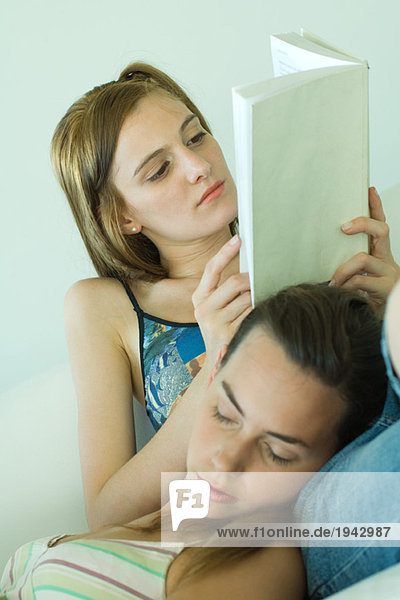 Junge Frau auf der Couch Lesebuch  Freund ruht Kopf auf dem Schoß  Augen geschlossen  Schrägsicht