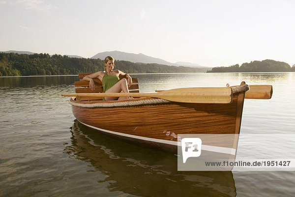 Junge Frau auf einem Ruderboot im See sitzend