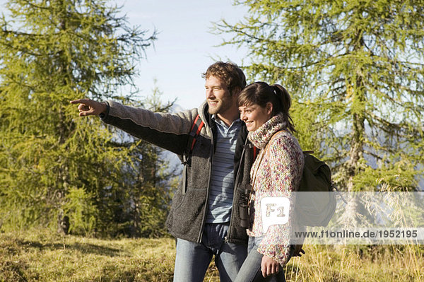 Ein junges Paar  das auf der Wiese spazieren geht  ein Mann  der darauf zeigt.