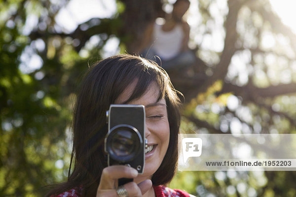 Young woman holding camera  young man sitting on tree house