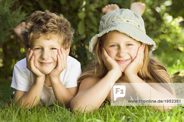 Junge und Mädchen (6-9) auf Gras liegend  Portrait