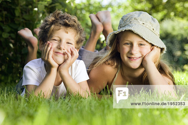 Junge und Mädchen (6-9) auf Gras liegend  Portrait