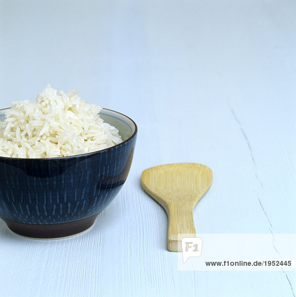 Cooked rice in a dish  wooden spoon aside