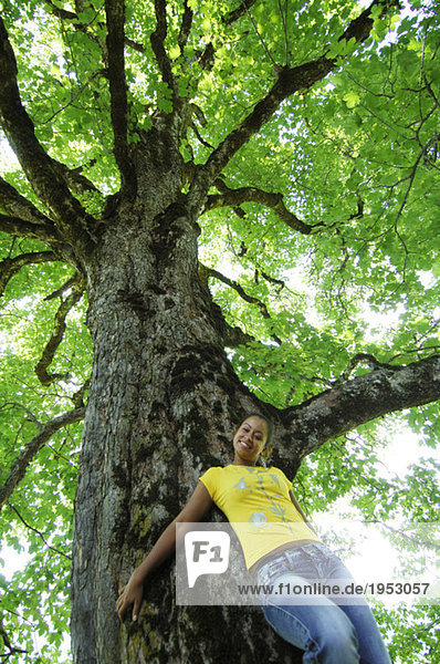Junge Frau an Baum gelehnt  Portrait