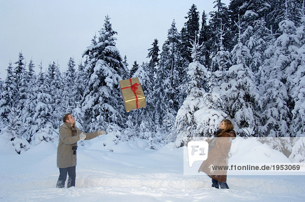 Couple playing with Christmas gift in snow