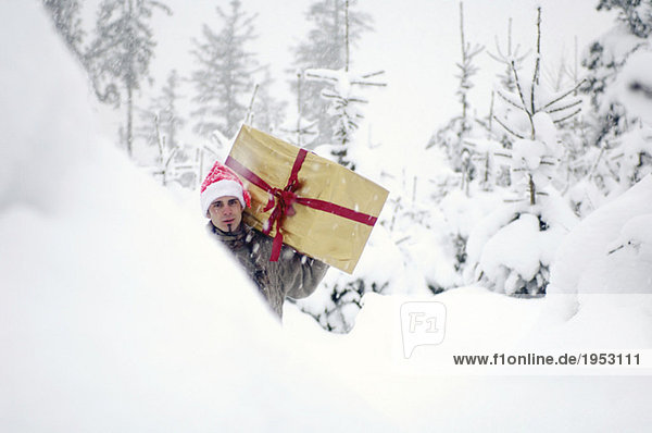 Young man walking in snow  carrying gift