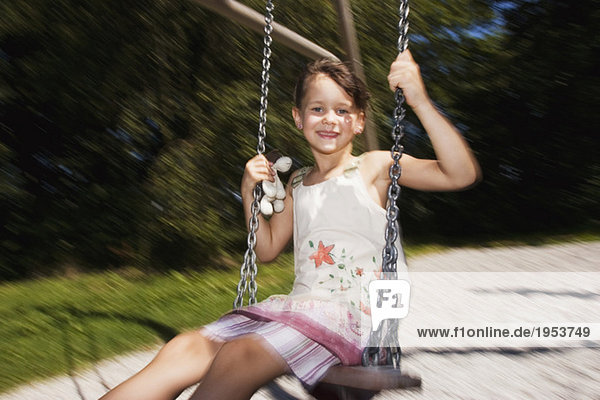 Girl (7-9) sitting on swing  smiling