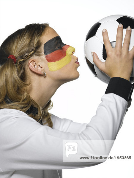 Frau mit deutscher Flagge auf Gesicht gemalt und in deutschem Fußballkleid küssend Fußball  Nahaufnahme