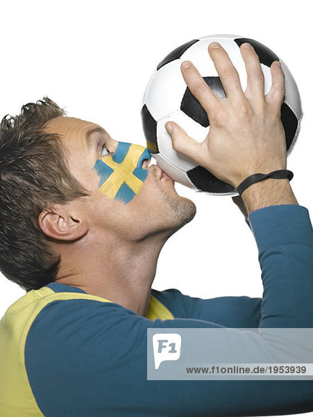 Junger Mann mit Schwedenflagge auf Gesicht gemalt