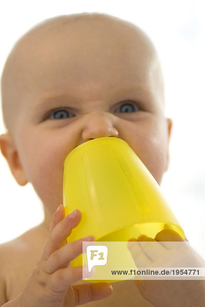 Junge (6-12 Monate) mit gelber Tasse,  Nahaufnahme