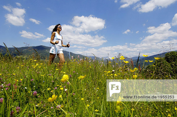Young woman Nordic walking in meadow  Germany  smiling  low angle view