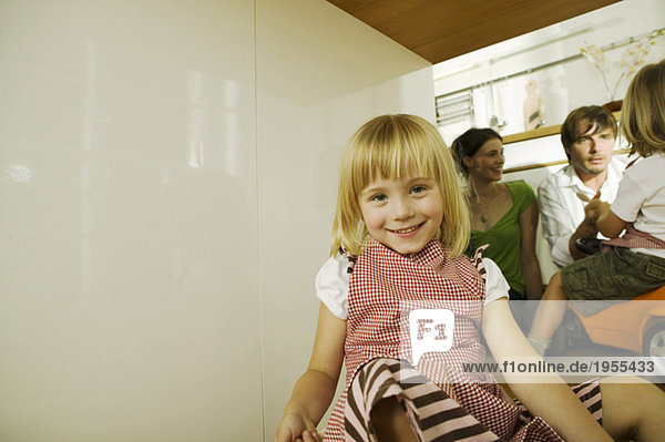 Kleines Mädchen (4-5) in der Küche  Portrait  Eltern im Hintergrund