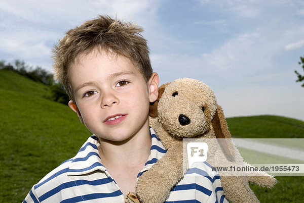 Junge (4-7) mit Spielzeughund auf Schulter,  Portrait,  Nahaufnahme