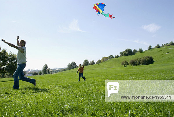 Father and son (4-7) flying kite in park