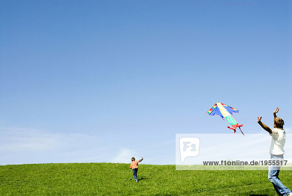 Germany  father and son (6-7) flying kite in meadow