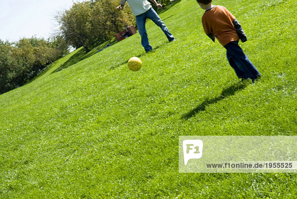 Father and son (4-7) playing football  low section