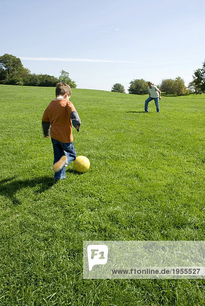 Vater und Sohn (4-7) spielen Fußball im Park