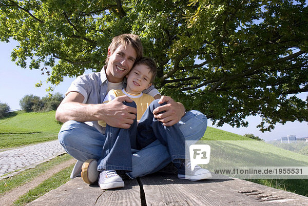 Vater und Sohn (4-7) sitzend auf Bank  Portrait