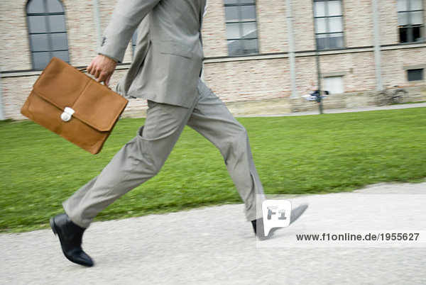 Businessman walking with briefcase  low section  (blurred motion)