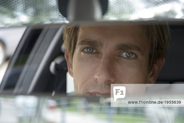 Businessman looking into rear view mirror  close-up