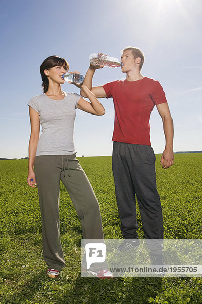 Junges Paar stehend und trinkend aus der Wasserflasche