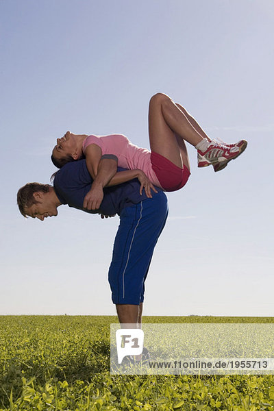 Junges Paar beim Gymnastizieren auf der Wiese  Seitenansicht