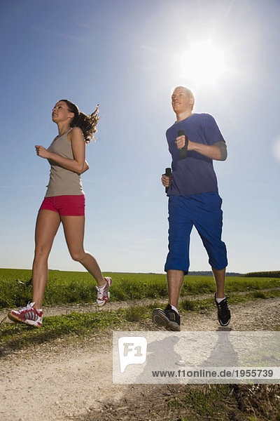 Young couple jogging,  man carrying dumbbells