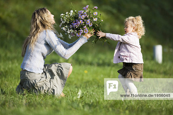 Tochter schenkt Mutter Blumenstrauß  Seitenansicht