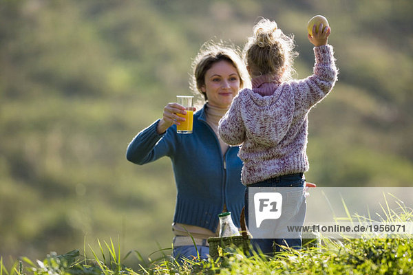 Mother with daughter in meadow,  having picnic