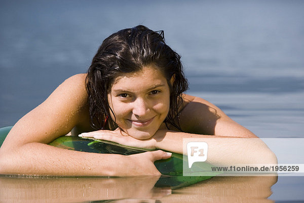 Young woman lying on floating tyre in lake