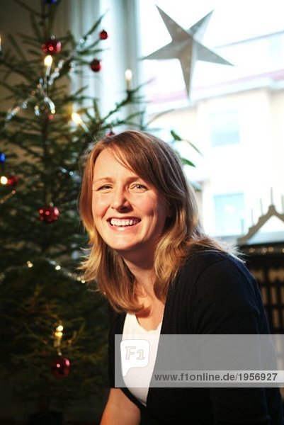 Frau lacht vor dem Weihnachtsbaum