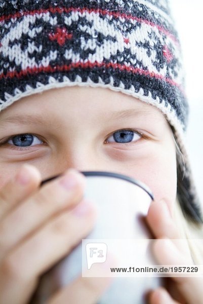 Girl in winter hat drinking from thermos jug