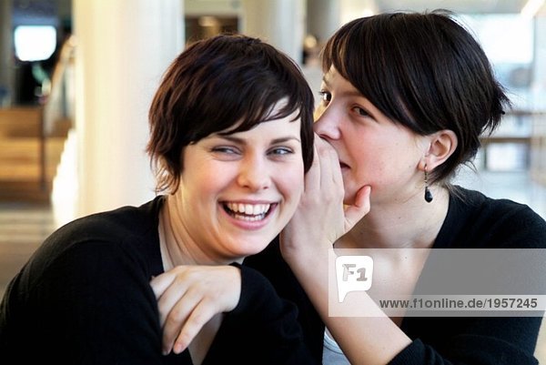 Girl whispering in friends ear