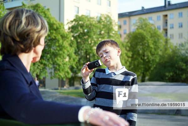 Boy taking a picture of grandmother with a cellphone camera