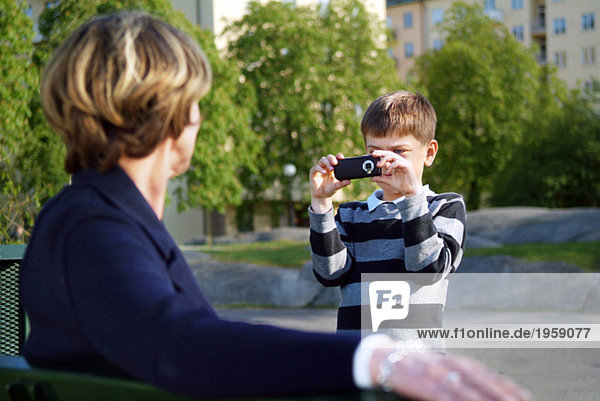 Junge fotografiert Großmutter mit der mobilen Kamera