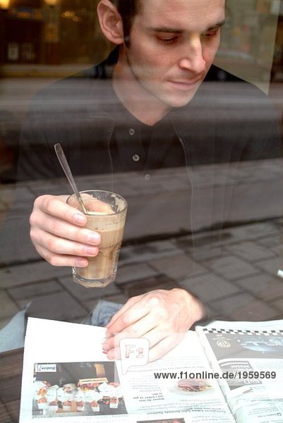 Mann liest und hält Kaffeeglas