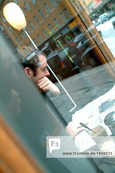 Mann liest Papier in einem Café