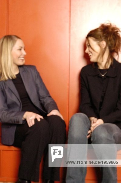 Zwei Frauen an der roten Wand lachend