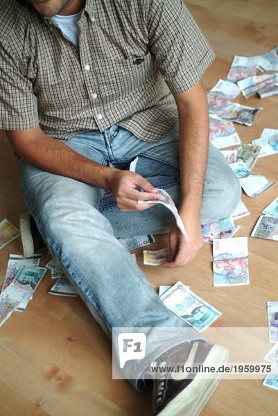 Junger Mann sitzend mit Geld