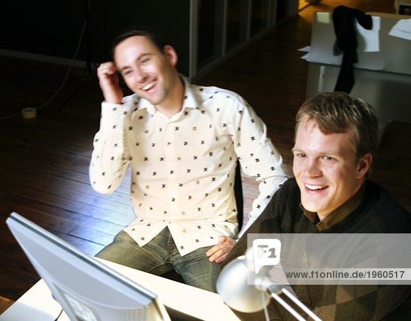 Two happy young men with computer