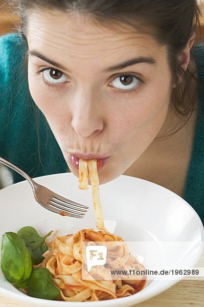 Junge Frau isst Bandnudeln mit Tomatensauce