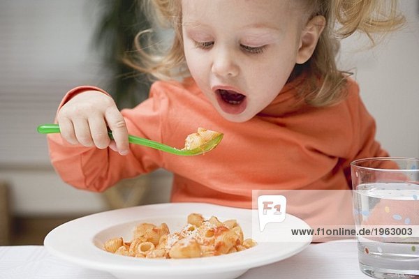 Kleines Mädchen isst Nudeln mit Tomatensauce und Parmesan