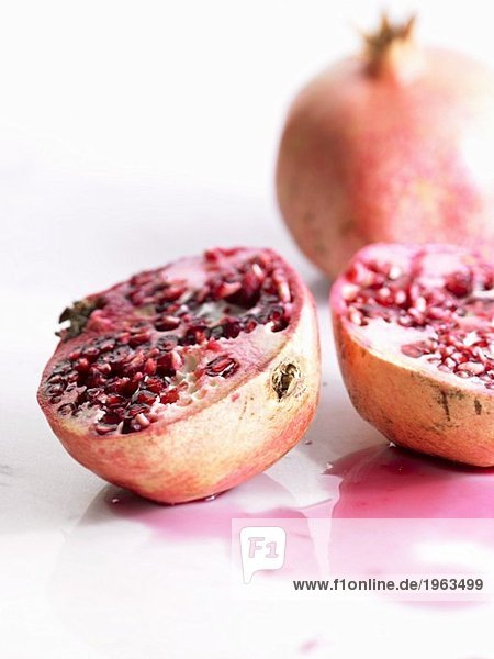 One halved and one whole pomegranate